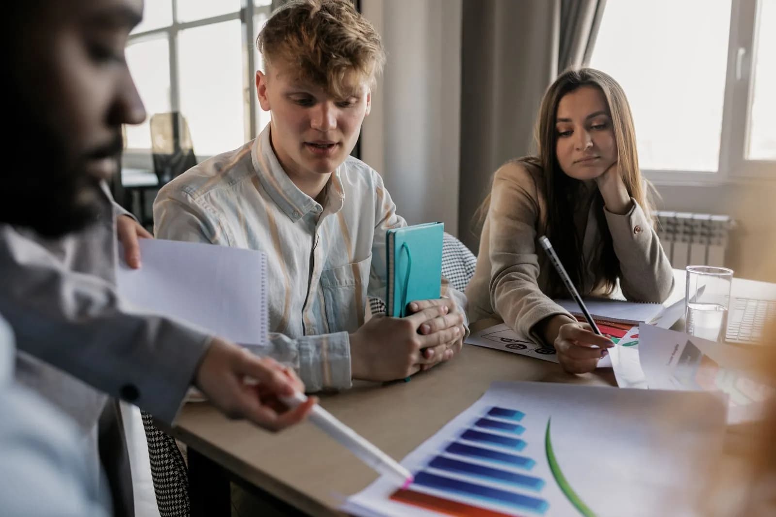 A diverse team of young professionals engaged in a business meeting analyzing graphs and data
