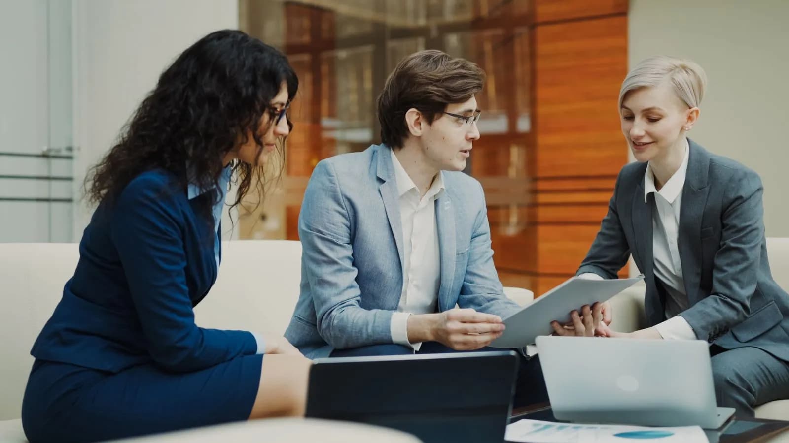 Three professionals discussing a tablet around an office table