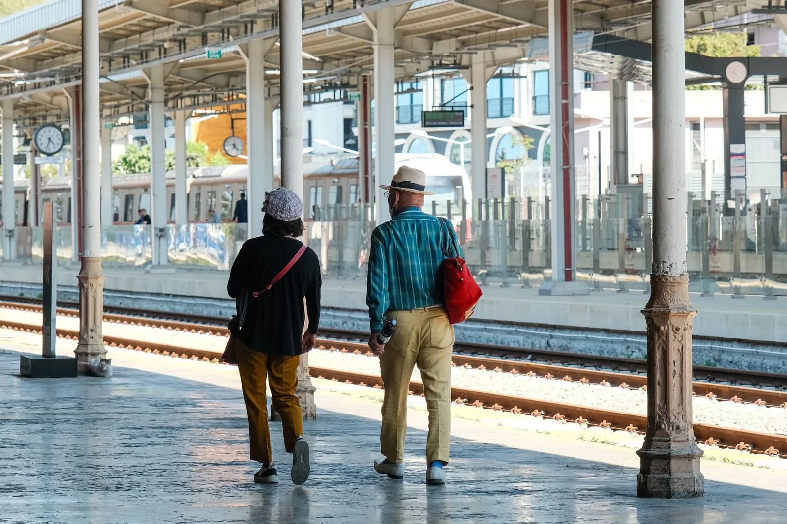 An older couple travelling together through a sunlit station