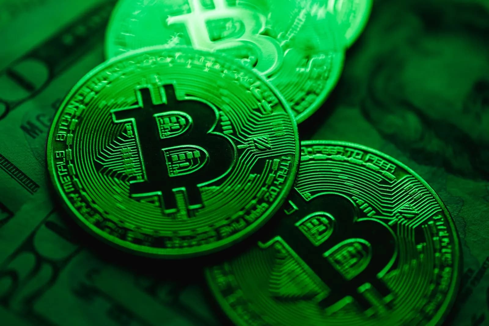 Close-up image of shiny Bitcoin coins with a digital green light effect, symbolizing blockchain technology.