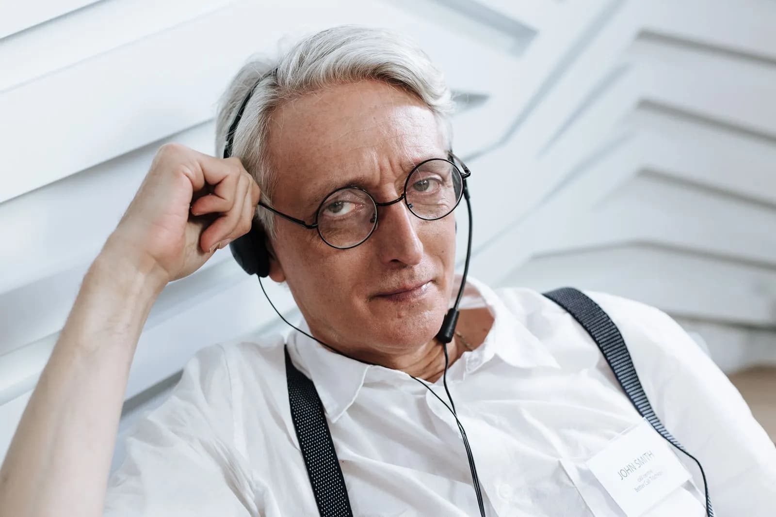 Senior man with glasses and headset working in a customer support role, indoors