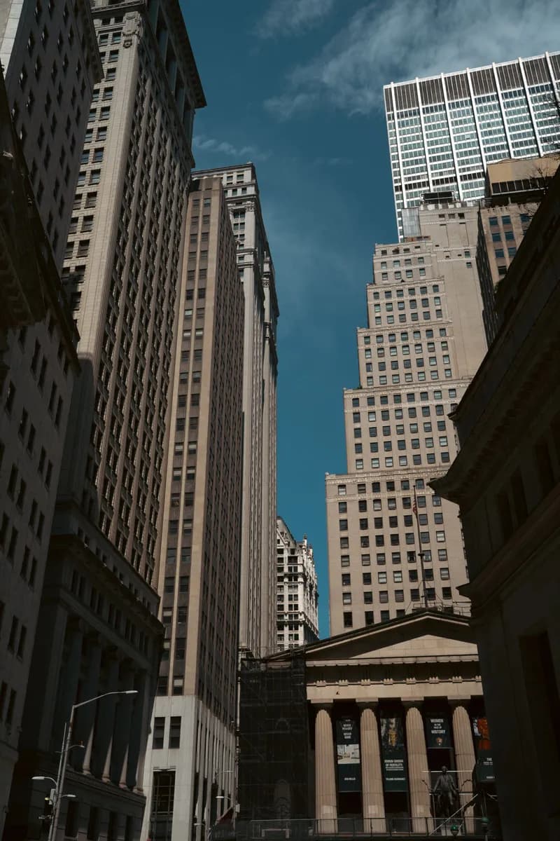 Looking up at towering skyscrapers in New York's Financial District under a clear blue sky.
